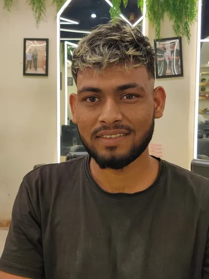 A smiling client with his new haircut, featuring a clean fade and a stylishly messy, highlighted top.