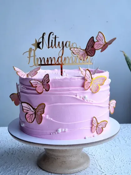 A beautiful lavender-colored whipping cream cake with a textured finish. The cake is decorated with delicate wafer paper butterflies.