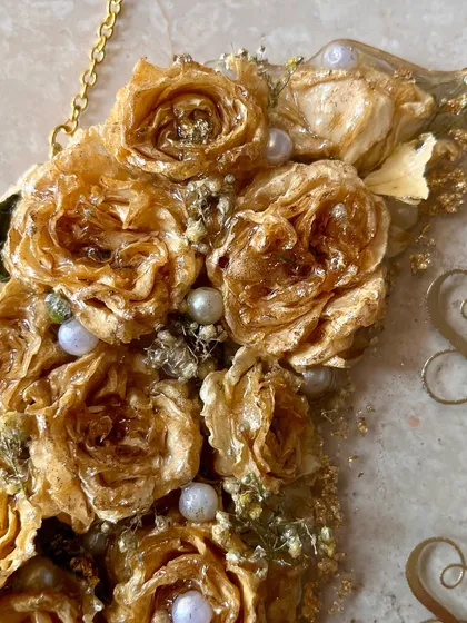 A close-up of the 3D preserved golden roses and pearls on a wall-hanging frame. The detail and craftsmanship in each flower are what make these pieces so special.
