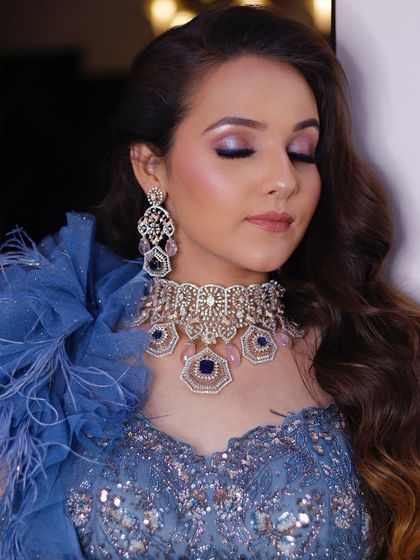 This shot showcases the complete cocktail look, including the soft waves in the hair and the elegant feathered shoulder detail of the gown. The makeup ties the entire glamorous look together.