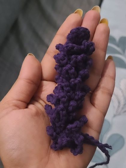 A detailed, in-hand view of one of my crocheted lavender stems. I use a rich purple yarn and a special stitch technique to create the textured look of real lavender buds. These add a lovely touch of color and detail to my floral arrangements.