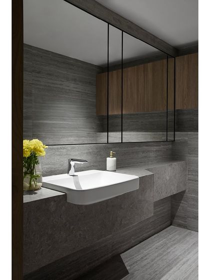 The washroom on the mezzanine level of the Blue Sea Banquet. The design is sleek and modern, with dark grey stone walls, a floating vanity, and mirrored panels that continue the design language from the main space.