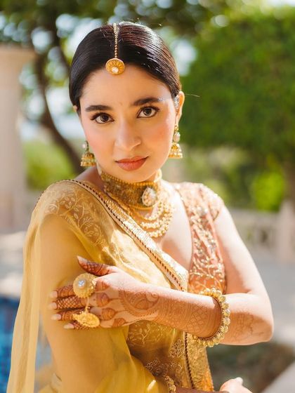 A close-up of Shree's Haldi jewellery, including a Borla for a Rajput touch and layered gold necklaces. The entire look is a beautiful fusion of cultures.