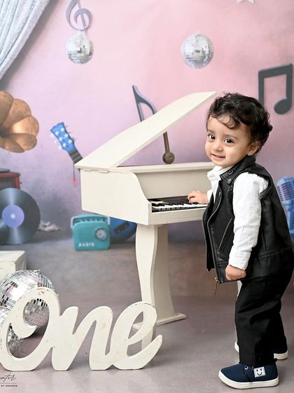 A little rockstar in the making. Dressed in a leather vest, this one-year-old is ready to play a tune on his piano in this cool, music-themed studio session.