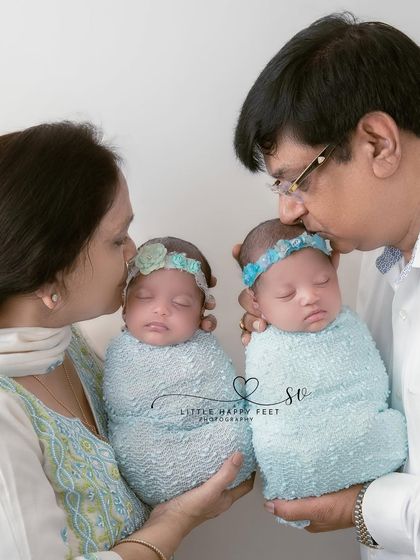 Generations of love. Grandparents holding their precious twin granddaughters is a moment of immense joy and a priceless family heirloom.