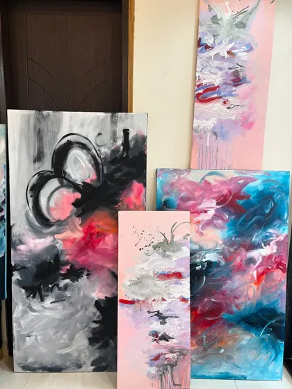 A collection of abstract paintings in my studio, all featuring a vibrant pink and blue color palette. This shows the variety in size and composition I can create within a single theme.