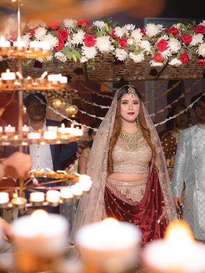 A beautiful shot of the bride during her grand entrance, framed by the warm glow of candles, making her look truly radiant.