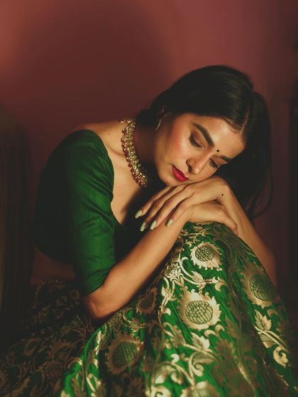 A close-up portrait capturing a moment of serene emotion. The way the light falls on the model's face and the rich green fabric of her outfit creates a painterly and artistic final image.