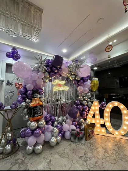 For this 40th birthday, we went for a classy and fun theme. The setup includes a balloon arch in purple and silver, a shimmer curtain backdrop, large marquee numbers, and even a fun whiskey bottle foil balloon to match the party vibe.