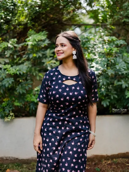 A candid and happy outdoor portrait. The model, dressed in a comfortable printed kurta, looks away with a bright smile, creating a warm and natural lifestyle shot.