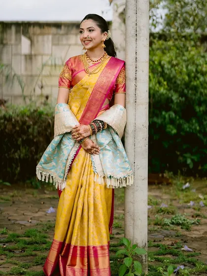 A full-length view of this stunning Maharashtrian bride. The makeup is kept elegant and clean to complement the rich colors and textures of her yellow and pink saree and the delicate shawl.