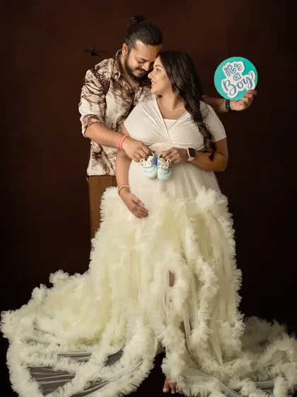 A fun gender reveal moment in the studio. Using props like tiny baby shoes and an "It's a Boy!" sign makes the announcement feel personal and joyous.