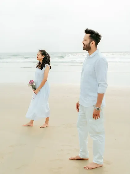 A pensive and stylish portrait of the couple looking out at the ocean, capturing a quiet moment of reflection.