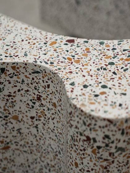 The undulating surface of the terrazzo bookshelf, designed to hold books and objects within its curves. It's a perfect example of how we merge form and function.
