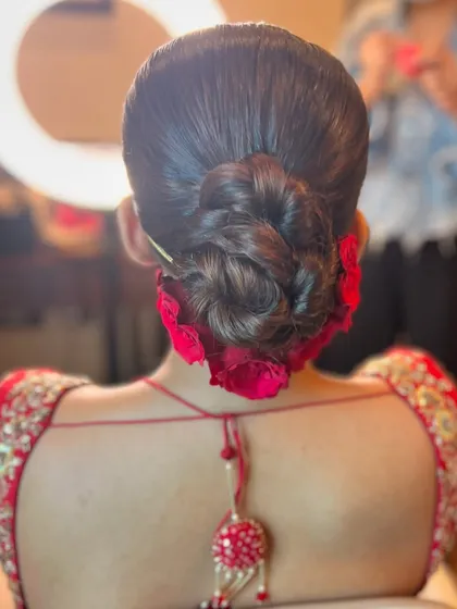 A classic braided bun adorned with fresh red roses. This is a bold and beautiful statement hairstyle for a bride.