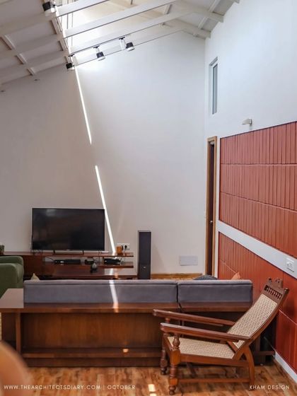 A terracotta-tiled accent wall adds warmth and texture to the living space, contrasting with the clean white walls. The simple, comfortable furniture is chosen to complement the natural and earthy material palette.