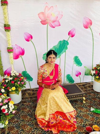 The full view of the client seated, showcasing the beautiful drape of the half saree and the complementary makeup and hair.