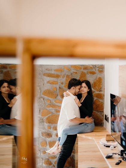 A creative reflection shot. This image captures their embrace from a unique perspective, adding an artistic and intimate feel to their indoor pre-wedding shoot.