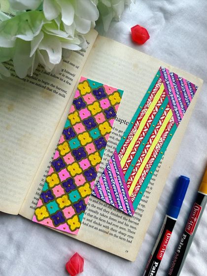A pair of patterned bookmarks, one with a floral-like geometric design and the other with colorful diagonal stripes.