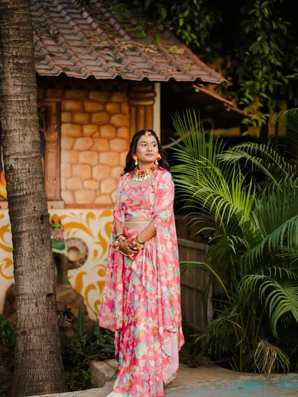 A beautiful outdoor shot of a client ready for her Haldi or Mehendi. The floral outfit is paired with matching floral jewelry and fresh, natural makeup.