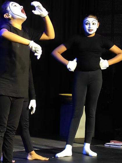 Two students fully immersed in their mime performance. The stark black costumes and white makeup help focus the audience's attention on their expressive movements and storytelling.