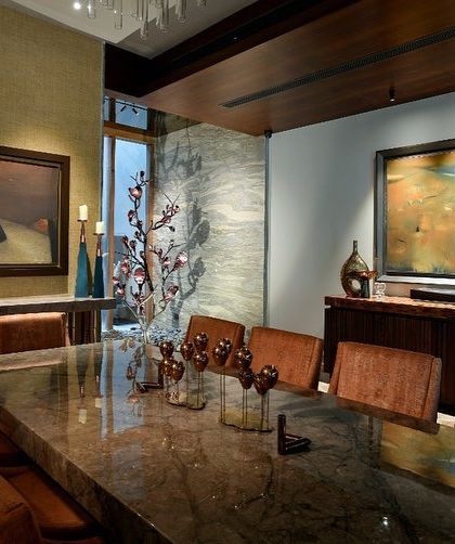 A dining room where art and atmosphere are paramount. The moody lighting, dark marble table, and abstract paintings create a sophisticated space for entertaining.