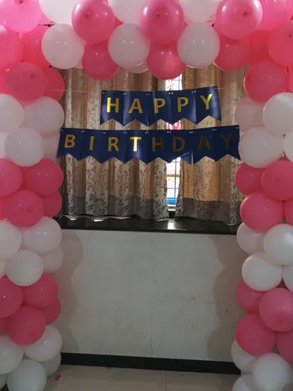 A straight-on view of the pink and white balloon arch with the birthday banner.