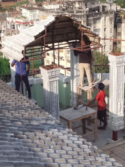 The beginning stages of the custom terrace mandir, showing the structural framework and the first stone pieces being lifted into place.