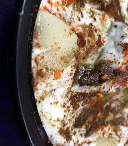 A bowl of freshly prepared boondi raita, seasoned with spices. It's the perfect cooling side dish to accompany our spicy curries.