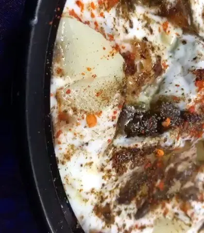 A bowl of freshly prepared boondi raita, seasoned with spices. It's the perfect cooling side dish to accompany our spicy curries.