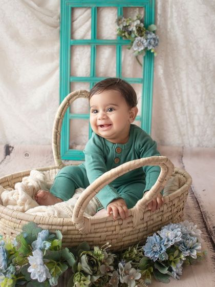 Another happy shot from a six-month milestone session. His bright smile lights up the frame in this cozy basket setup.
