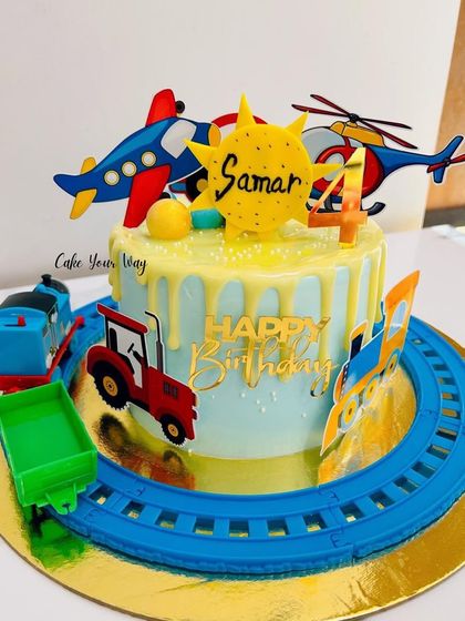All aboard the birthday express. This cake is perfect for a little one who loves all things that go, featuring Thomas the Train, a tractor, and airplanes.