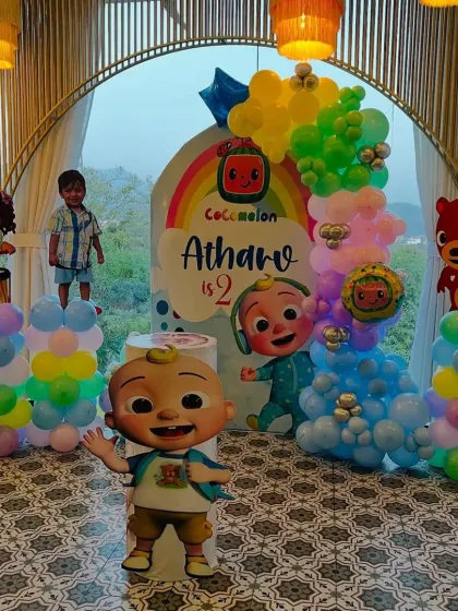 This Cocomelon setup for Atharv's 2nd birthday features multiple character cutouts, a personalized backdrop, and a pastel balloon garland.