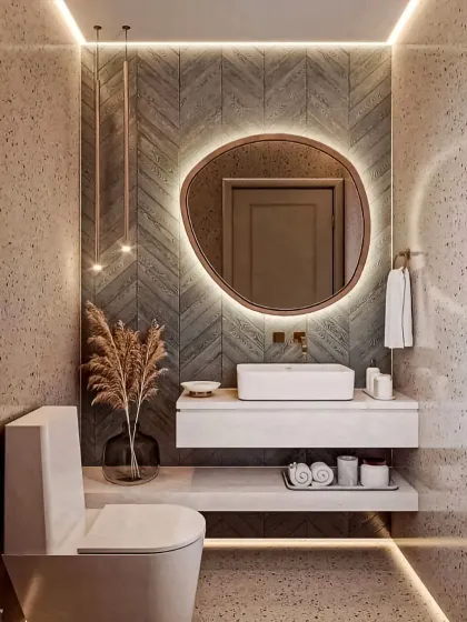 This bathroom design combines textured walls with modern fixtures for a spa-like feel. Key features include a floating vanity with a vessel sink, an organically shaped backlit mirror, and layered ambient lighting to create a warm and inviting retreat.