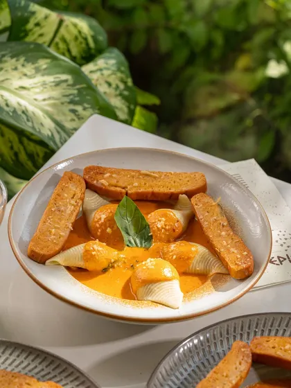 Stuffed conchiglie pasta shells in a creamy tomato sauce. The lighting highlights the texture of the sauce.