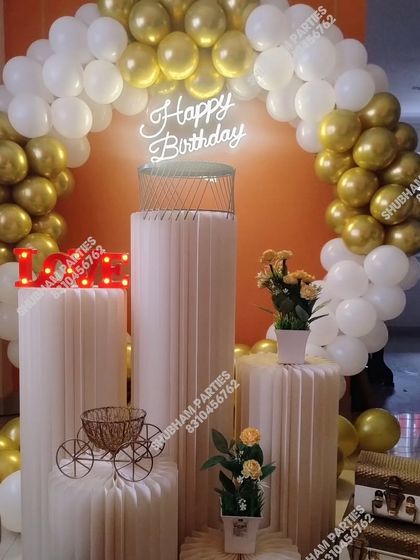A beautiful gold and white balloon arch with elegant plinths, perfect for a sophisticated birthday or anniversary party.