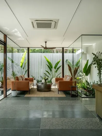 The reception at the Soul Spring Experience Centre, where a warm brass-clad desk contrasts with the cool Kota stone flooring. The waiting area is encased in glass, surrounded by plants and water to create a calming, zen-like atmosphere.