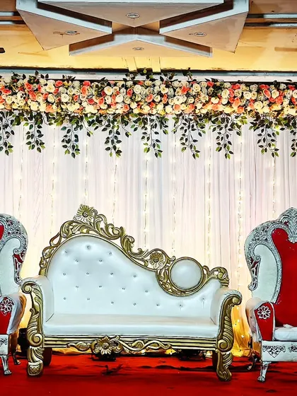 For only 10,000, you can have this traditional stage setup. It includes a white and gold chaise lounge, matching royal chairs, and a simple floral and light backdrop.