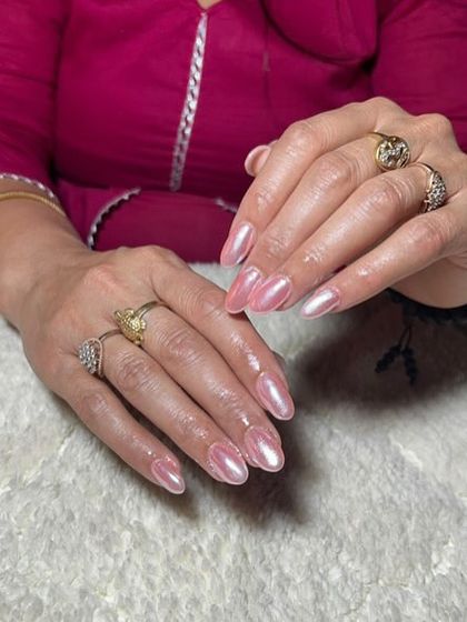 A beautiful pearlescent pink chrome finish on almond-shaped nails, giving them a soft, iridescent glow.