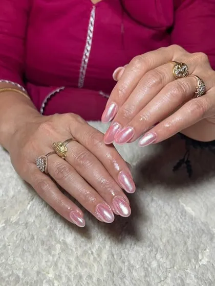 A beautiful pearlescent pink chrome finish on almond-shaped nails, giving them a soft, iridescent glow.
