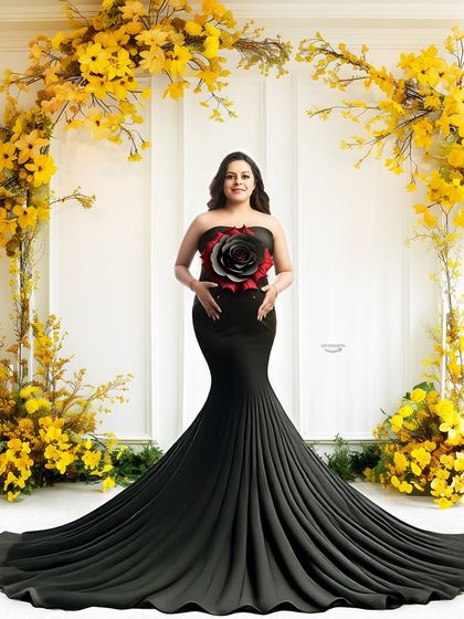 A striking contrast of a black mermaid gown against a vibrant yellow floral arch. The bold red and black flower detail on the dress adds a unique, artistic touch to this dramatic maternity portrait.