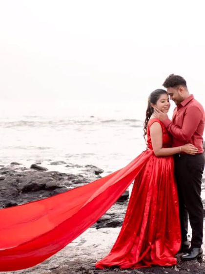 An intimate close-up by the sea. Even without the full trail in view, the rich red color and soft fabric of the gown create a feeling of romance and connection.