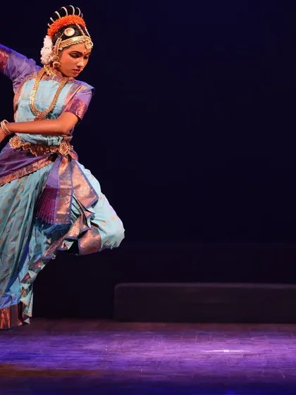 A solo performer captured in a powerful 'tribhanga' pose during the Sadhana festival, demonstrating her mastery of classical Bharatanatyam technique.