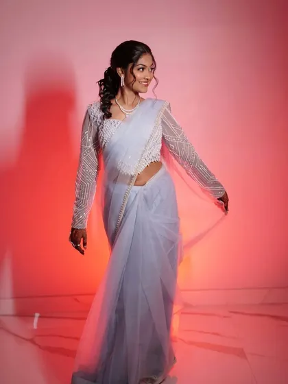 A full-length view of her elegant sangeet outfit. The makeup is balanced to complement the intricate details of her saree and blouse.