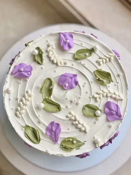 A top-down view of the wildflower cake, showcasing the artistic arrangement of the purple and white blooms.