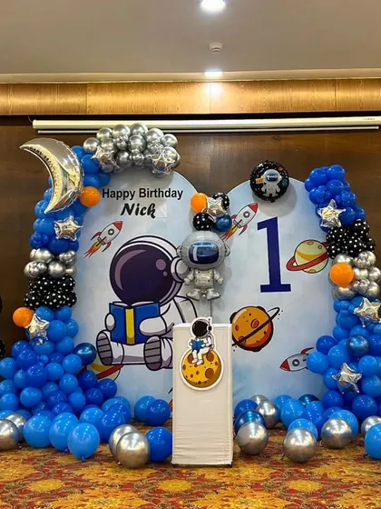 A wider view of the astronaut party setup, including a "Happy Birthday" balloon pillar.