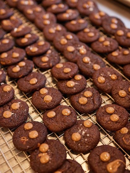 Freshly baked chocolate cookies cooling on a rack, ready to be packed into our gift jars and boxes.