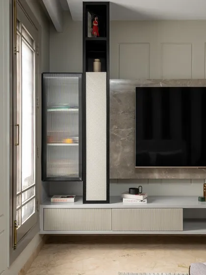 A close-up of the TV unit, which features a mix of open and closed storage with fluted glass doors. The design is both functional and stylish, maintaining the room's modern aesthetic.