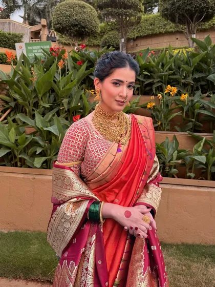 A beautiful shot amidst lush greenery. The natural light highlights her glowing skin and the intricate details of her traditional Maharashtrian bridal look.