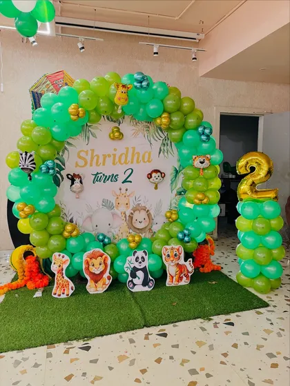 For a kid's second birthday, I created this fun jungle theme. The setup includes a custom backdrop with cartoon animals, a circular balloon arch in shades of green, and animal cutouts to bring the safari party to life.